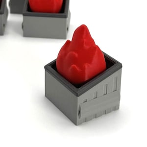 May include: Four miniature, gray, square containers each hold a bright red flame-shaped object. The objects appear to be 3D-printed. The containers are arranged on a white surface.