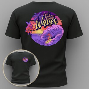 Peut inclure: T-shirt noir avec un motif coloré au dos représentant un surfeur sur une vague, un coucher de soleil et le texte "Let's Catch Some Waves". Une version plus petite du motif est sur le devant.