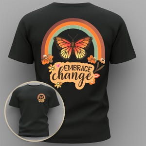 Pode incluir: Camiseta preta com um design colorido com borboleta, arco-íris e flores. O texto "Embrace Change" é exibido abaixo. Uma versão menor da camiseta é mostrada em uma inserção circular.