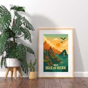 May include: Framed art print featuring a stylized landscape with the text "Visit Isle of Berk." The artwork depicts Viking-style buildings on a cliffside, mountains, a sunset, and flying dragons. The print is in a wooden frame.