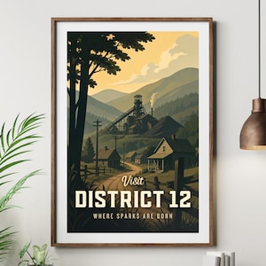 May include: A framed poster featuring a landscape scene of a town in a valley. The poster reads "Visit DISTRICT 12" with the tagline "WHERE SPARKS ARE BORN". The colour palette includes shades of brown, green, and yellow.