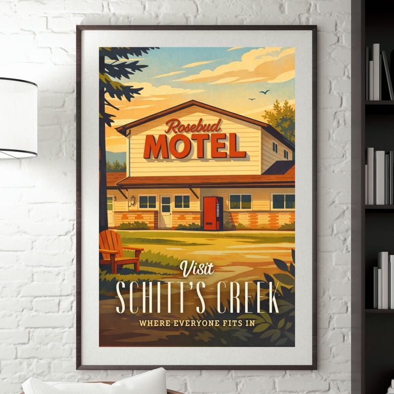 May include: Framed poster featuring the Rosebud Motel from Schitt's Creek. The artwork depicts the motel with a red door and sign, set against a sky with birds. The text "Visit Schitt's Creek" is displayed below the motel, with the tagline "Where Everyone Fits In."