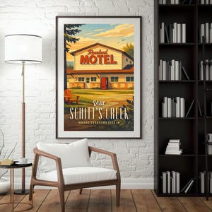 May include: A framed poster featuring the Rosebud Motel from Schitt's Creek. The artwork depicts the motel with a red door, set against a sunset sky. The text "Visit Schitt's Creek" is prominently displayed below the motel illustration.