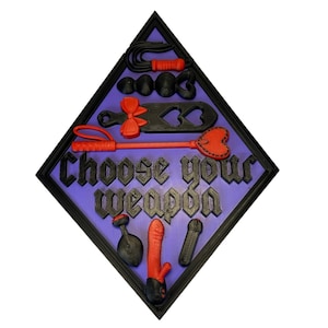 May include: A diamond-shaped wall plaque with a purple background and black border. It features the text "Choose your weapon" in black gothic lettering, surrounded by various 3D-printed black and red adult novelty items, including a whip, paddle, and vibrator.