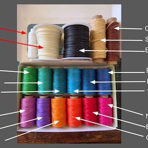 Peut inclure: Une s&eacute;lection de cordons et de fils color&eacute;s est pr&eacute;sent&eacute;e dans une bo&icirc;te. La s&eacute;lection comprend du blanc, ivoire, noir, ch&acirc;taigne, paille, et une gamme de couleurs vives comme &eacute;meraude, vert printemps, aigue-marine, lavande, violet et orange n&eacute;on. Le texte indique l'&eacute;paisseur de chaque cordon.
