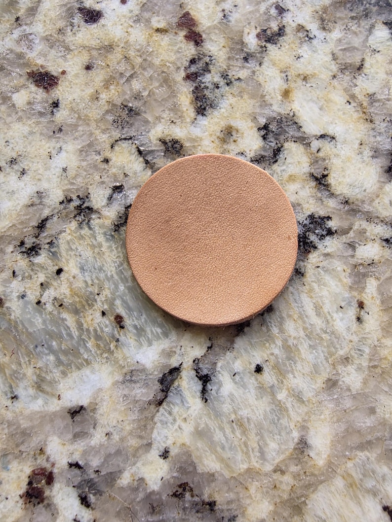 Peut inclure: Un dessous de verre rond en cuir brun clair. Le dessous de verre est de couleur unie et a une surface lisse. Il est con&ccedil;u pour prot&eacute;ger les surfaces de la condensation des boissons. Diam&egrave;tre d'environ 8 cm.