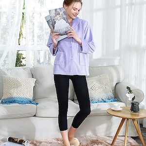 Puede incluir: Chaqueta de pana lila con cierre de botones y dos bolsillos delanteros. La chaqueta se combina con leggings negros y zapatillas marrones forradas de piel. Se sostiene una revista en las manos.