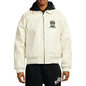 May include: Cream-colored jacket with a black hood and collar. The jacket features a zipper closure, ribbed cuffs, and a ribbed hem. The left chest displays a black emblem with the text "AVIREX" and "1975".