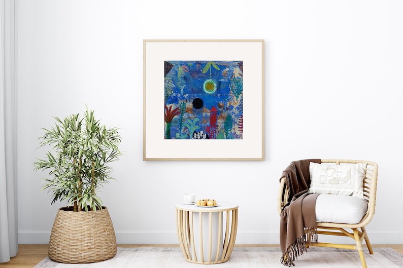 May include: Abstract art print in a wooden frame. The artwork features a blue background with colourful shapes, including a black circle, a yellow circle, and red and green plant-like forms. The print is displayed in a bright room with a plant and a chair.