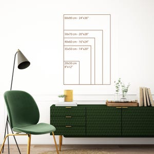 May include: A display of various rectangular art print sizes, including 8"x12", 14"x20", 16"x24", 20"x28", and 24"x36". The sizes are displayed on a white wall above a dark green cabinet. A green chair and a lamp are in the foreground.