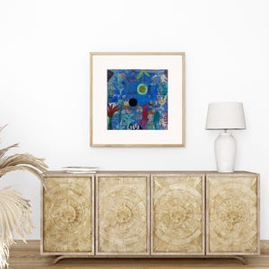 May include: A framed abstract art print with a blue background and colourful shapes. The artwork is displayed above a wooden cabinet with a white lamp. The cabinet has four doors with a circular design.