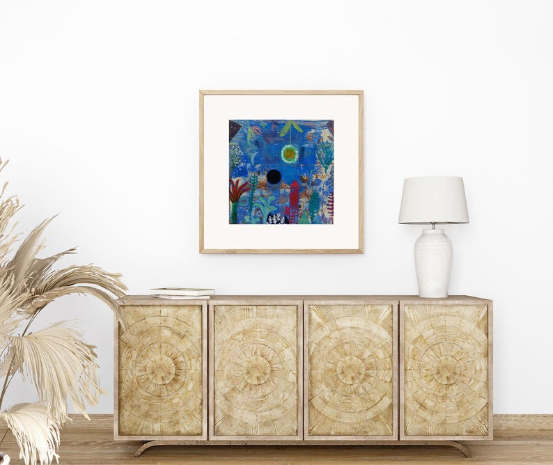 May include: A framed abstract art print with a blue background and colourful shapes. The artwork is displayed above a wooden cabinet with a white lamp. The cabinet has four doors with a circular design.