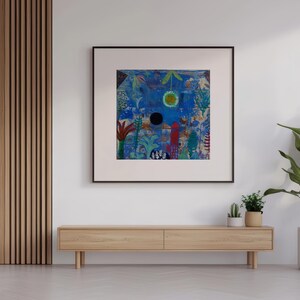 May include: An abstract artwork in a black frame, featuring blue and green hues, hangs on a white wall. Below, a wooden cabinet is positioned. A large potted plant is to the right. The room has a modern, minimalist design.