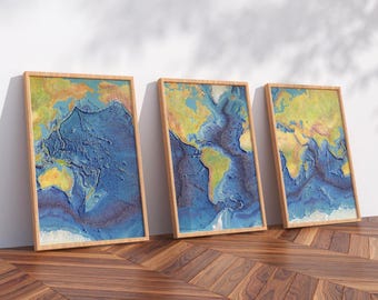 May include: Three framed relief maps of the world's ocean floors. The artwork features a detailed depiction of the ocean depths in shades of blue, yellow, and brown, set within wooden frames. The maps are leaning against a white wall.