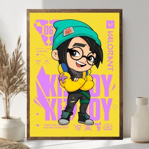 May include: A framed poster featuring a cartoon character in a teal beanie and glasses, wearing a yellow jacket. The background is yellow with purple text that says "KAY/O" and "VALORANT". The text "DEFY THE LIMITS" is also visible.