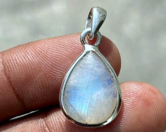 May include: A teardrop-shaped pendant with a moonstone center, set in a silver metal frame. The moonstone displays a soft, iridescent blue and white color. The pendant has a small loop at the top for a chain.