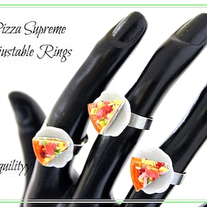 May include: Three adjustable rings featuring miniature pizza slices with toppings. The rings are on a black hand model. The text "Pizza Supreme Adjustable Rings" and "Tranquility" are visible in the image.
