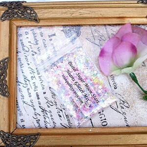 May include: A small clear plastic bag filled with pastel colored glitter, hearts, and stars. The bag is labeled "Pastel Sugar Moon Stars Hearts Glitter Mix" and "tranquilityy.etsy.com".