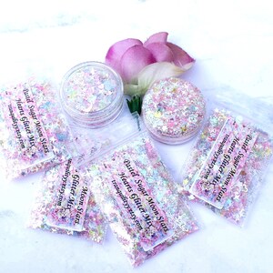 May include: Pastel pink, blue, and white glitter mix in small clear plastic bags with the text "Pastel Sugar Moon Stars Hearts Glitter Mix tranquilityy.etsy.com".
