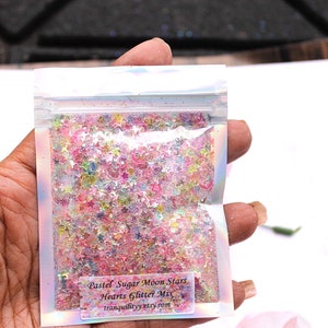 May include: A small clear plastic bag filled with pastel pink, blue, and green glitter stars and hearts. The bag has a label that reads "Pastel Sugar Moon Stars Hearts Glitter Mix tranquilitycrystals.com".