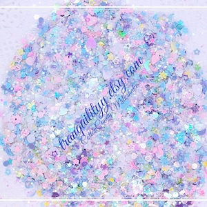 Op de afbeelding: Een close-up van een verscheidenheid aan iriserende glitter in tinten blauw, roze en paars. De glitter is verspreid over een lichtpaarse achtergrond. De tekst "tranquility.etsy.com Cotton Candy Milkshakes" is zichtbaar in de afbeelding.