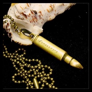May include: A gold bullet necklace with a chain and a bullet pendant that says "ECLOS FIRE".