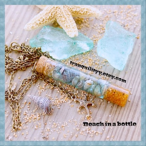 May include: A glass vial necklace with a cork stopper filled with sand, seashells, and a starfish charm. The necklace is on a wooden surface with a starfish and sea glass.