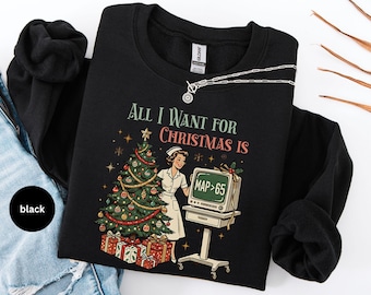 May include: A black crewneck sweatshirt featuring a graphic print with the text "All I Want For Christmas Is" above a nurse standing next to a decorated Christmas tree, presents, and a medical monitor displaying the text "MAP > 65".