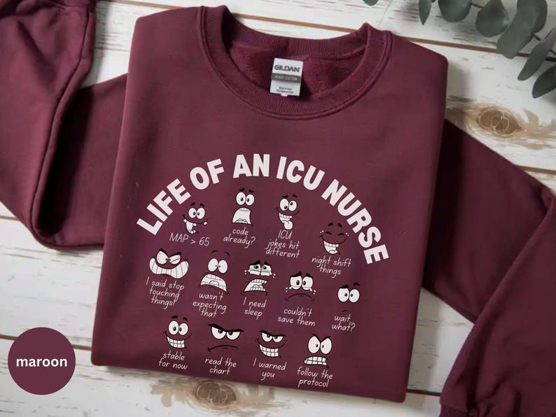May include: Maroon crewneck sweatshirt with the text "LIFE OF AN ICU NURSE" and various cartoon faces expressing different emotions. The sweatshirt also has the word "maroon" printed on it.