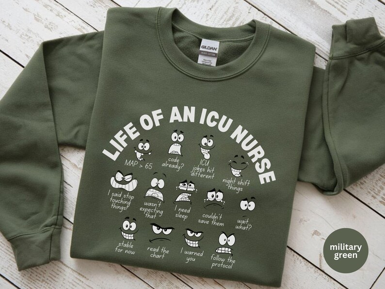 May include: Military green sweatshirt with the text "LIFE OF AN ICU NURSE" and various cartoon faces expressing different emotions. The sweatshirt also has phrases like "code already?" and "wait what?"