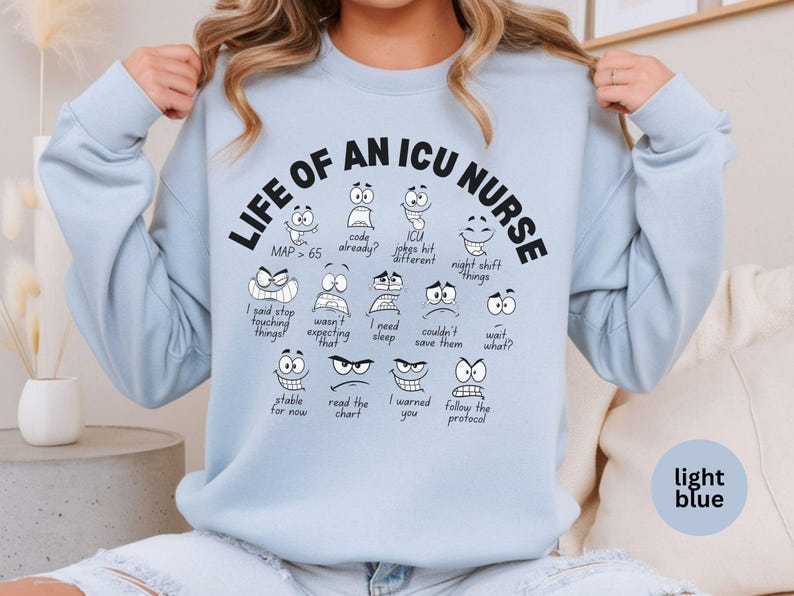 May include: Light blue sweatshirt with the text "LIFE OF AN ICU NURSE" and various cartoon faces with different expressions. The sweatshirt also has the text "MAP > 65".