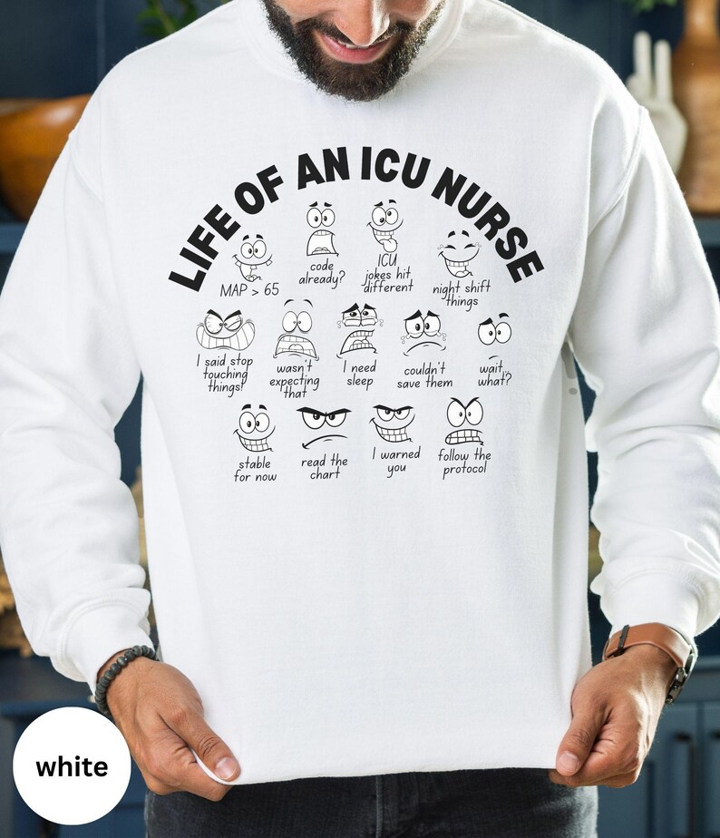 May include: White sweatshirt with the text "LIFE OF AN ICU NURSE" in black, featuring various cartoon faces expressing different emotions. The sweatshirt also includes phrases like "MAP > 65" and "code already?"