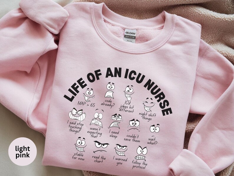 May include: Light pink sweatshirt with the text "LIFE OF AN ICU NURSE" in black, along with various cartoon faces expressing different emotions. The sweatshirt also features phrases like "MAP > 65" and "I need sleep."