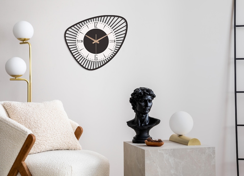 K&ouml;nnte beinhalten: Eine schwarz-wei&szlig;e Wanduhr mit einem einzigartigen, geometrischen Design. Die Uhr hat einen schwarzen Rahmen mit einer Reihe vertikaler Linien um das Zifferblatt. Das Zifferblatt ist wei&szlig; mit schwarzen Zahlen und Zeigern.