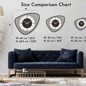 K&ouml;nnte beinhalten: Eine Gr&ouml;&szlig;envergleichstabelle zeigt drei schwarz-wei&szlig;e Wanduhren mit einem einzigartigen, asymmetrischen Design. Die gr&ouml;&szlig;te Uhr ist 69 cm breit und 60,5 cm hoch. Der Text "Size Comparison Chart" befindet sich oben.