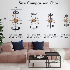 May include: A size comparison chart displays four mid-century modern wall clocks. The clocks are black with a circular wooden center and radiating arms. The largest clock is 33.8 inches high and 19.3 inches wide. The text "Size Comparison Chart" is at the top.
