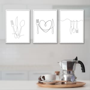 May include: Set of three framed minimalist art prints featuring line drawings of cutlery. The first print shows a fork, knife, and spoon. The second print has a fork, knife, and heart shape. The third print displays hanging cutlery. All prints are black and white.