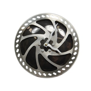 May include: A silver bicycle disc brake rotor repurposed as a clock with black hands. The clock face is black with a silver design.