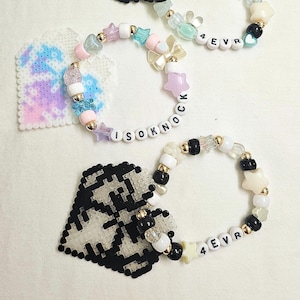 Puede incluir: Tres pulseras de cuentas con cuentas en forma de estrella, lazo y corazón en colores pastel, detalles dorados y cuentas de letras que deletrean "4EVR" e "ISOKNOCK". También hay dos formas de corazón de pixel art.
