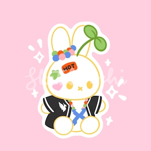 May include: A cartoon illustration of a white bunny with a black jacket, colorful accessories, and a green sprout on its head. The bunny has a "HOT" sticker and a pink heart. The background is pink.