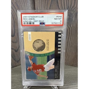 May include: A baseball card encased in a clear plastic holder. The card features Rick Ankiel of the St. Louis Cardinals in a pitching pose. The card includes a patch of dirt and text that reads "2001 Stadium Club".
