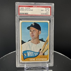 Könnte beinhalten: Eine 1965 Topps Baseballkarte von Gene Stephens in einer Schutzhülle. Die Karte zeigt Stephens in einem White Sox-Trikot mit Schlägern. Die Karte ist von PSA mit NM-MT 8 (OC) bewertet. Der Text lautet "WHITE SOX".