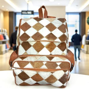 May include: A leather backpack in a diamond pattern of brown, white, and tan. It features a flap closure, a front zipped pocket, and two side pockets. The straps and handle are brown leather. The bag is designed for carrying items.