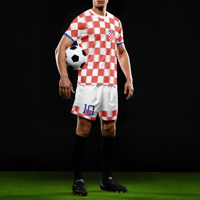 May include: A soccer player in a red and white checkered jersey and white shorts with the number 10. The jersey has blue trim and a Croatian flag patch. The player is holding a black and white soccer ball, wearing black socks and cleats.