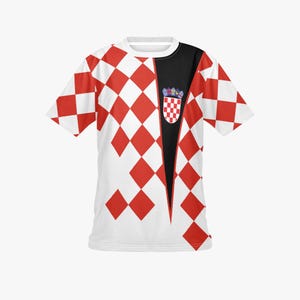 May include: White t-shirt with a red and white checkered pattern on the front and sleeves. The shirt has a black panel on the right side with a Croatian coat of arms emblem. The shirt is short-sleeved.