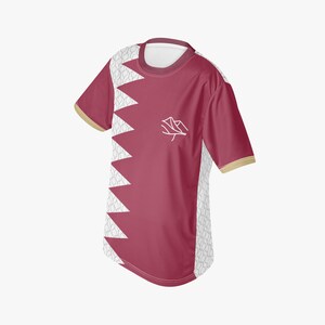 May include: Maroon and white short-sleeved t-shirt with a geometric design. The shirt features a white zigzag pattern on the left side and a white emblem on the front. The sleeves have a gold trim.