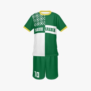 以下が含まれることがあります： 胸に「SAUDI ARABIA」の文字が入った、緑と白のサッカーユニフォーム。ジャージは黄色い襟と袖のトリムが付いています。ショーツは緑色で、白の数字「10」が入っています。