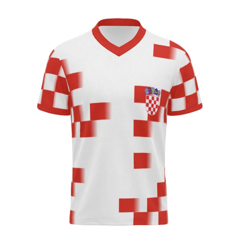 Op de afbeelding: Wit en rood voetbalshirt met een V-hals en korte mouwen. Het shirt heeft een patroon van rode vierkanten en een Kroatisch wapen op de borst. De mouwen en kraag zijn rood.