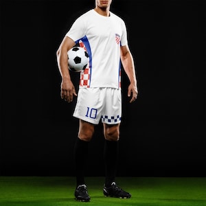 Peut inclure: Un uniforme de football blanc avec des d&eacute;tails rouges et bleus, orn&eacute; d'un &eacute;cusson du drapeau croate. Le short porte le num&eacute;ro 10 en bleu. Le joueur tient un ballon de football noir et blanc, debout sur une surface verte.
