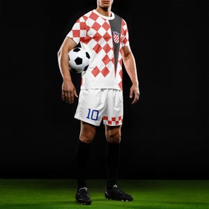 May include: A soccer uniform featuring a red and white checkered pattern on the jersey and shorts. The shorts have the number 10 in blue. The jersey has a black accent on the shoulder and a Croatian emblem. A soccer ball is held in the image.